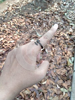 finger wears a black ring in the shape of a bent nail