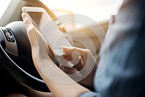 Finger of woman hand with blue jean shirt pressing mobile phone with empty screen and holding smart phone sitting inside a car