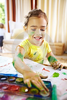 Fingerpainting genuis at work. an adorable little girl making a mess while painting. photo