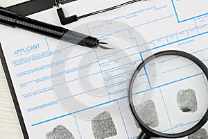 Fingerprints card police form on A4 tablet lies on office table with pen and magnifying glass