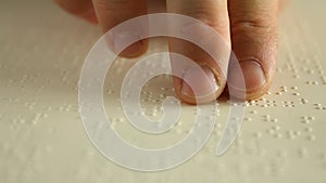 Fingers of an adult man reading a braille book. Closed-up