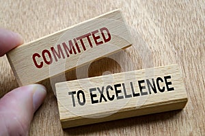 Fingers align wooden blocks that declare commitment to EXCELLENCE, reinforcing an unshakable focus on quality and continuous