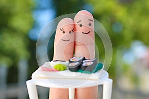 Fingers art of Happy couple. Man and woman eat sushi in cafe