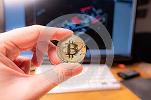 Fingers in black gloves hold a silver bitcoin on the keyboard background photo