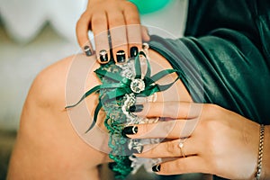 Fingers of the bride, with a beautiful manicure, keep on her leg a wedding garter
