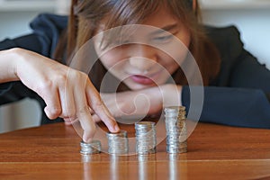 Fingers of businesswoman walking on coins with wooden desk