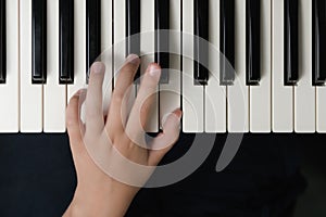 Fingers of a child on the piano keyboard. Close-up