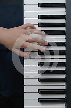 Fingers of a child on the piano keyboard. Vertical format. top view photo