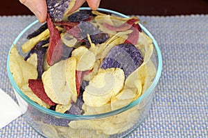 Fingers Choosing Red, Purple and Yellow Potato Chips