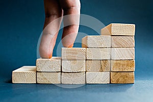 Fingers climbing the stairs made with wooden blocks. Concept of the success, career, goal achievement, hardworking.