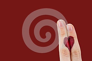 Fingers coupled together with drawn heart, isolated on red background, symbol of love