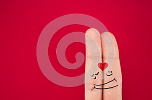 fingers coupled together with a painted heart, a cheerful smile, smileys, emojis, isolated on red background, the symbol of love photo