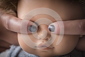 Fingers covering eyes of a doll