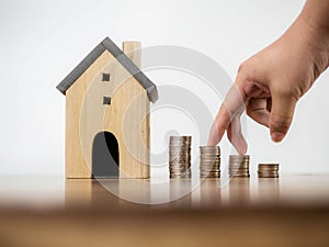 Fingers hand step forward on stack of coins and model house on white space background concept business finance growing idea