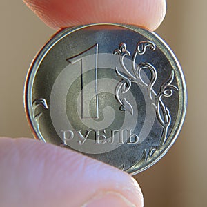 The fingers hold the Russian coin 1 one ruble. Close-up