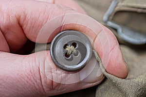 Fingers holding a brown plastic button