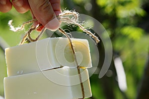 Fingers Holding Natural Handmade Soap Bars with String. Herbal Wellness Skin Care. Countryside Aromatherapy and Herbalism 