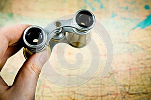 Fingers holding vintage silver binoculars - map on the background