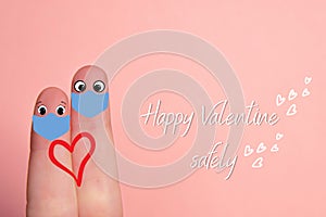 Fingers of love. Close-up of two fingers on pink background with drawn smile faces and surgical mask. San Valentin and pandemia