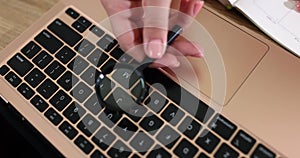 Fingers with a magnifying glass above the keyboard, closeup