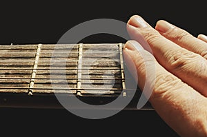 Fingers muffling the sound of the strings of an old acoustic guitar photo