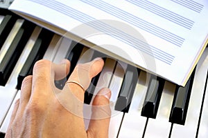 Fingers play black and white piano keys a notebook for sheet music lies learning music sheet music playing on the synthesizer