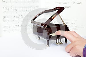 Fingers playing on small model of grand piano