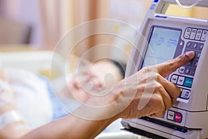Fingers press control panel for adjust Infusion pumps with blurry patient