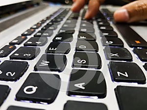 Fingers pressing keys on laptop keyboard. a close up view