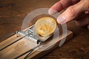 Fingers reaching for bitcoin in trap