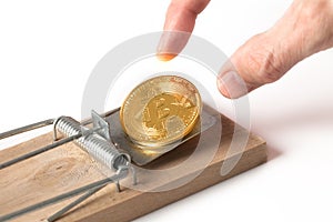Fingers reaching for bitcoin in trap isolated on white
