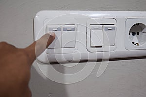 Fingers are turning offlight switch in the house, concept for energy saving reduce global warming
