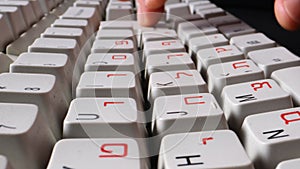 fingers typing text on a computer keyboard with English and Hebrew alphabet