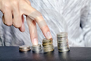 Fingers walk on piles of coins, symbolizing financial growth and progress in business. Concept of career growth and wage increases