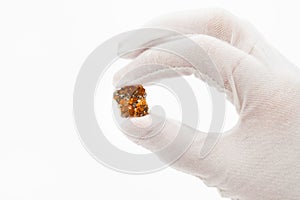Fingers in white glove holds spessartine crystals photo