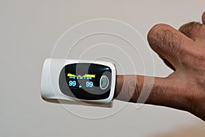 Fingertip pulse oximeter equipment connected to the index finger of a young man measuring oxygen saturation and heart rate