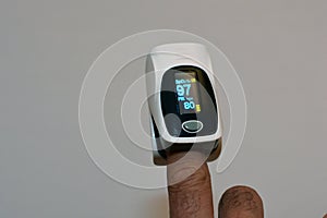 Fingertip pulse oximeter equipment connected to the index finger of a young man measuring oxygen saturation and heart rate