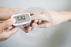 Fingertip pulse oximeter on the finger of young woman measuring heart rate pulse checking oxygen saturation SpO2 level in the photo