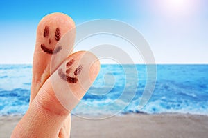 Fingertips with smiley faces at the beach