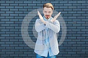 Finish, this is the end. Portrait of serious handsome young blonde man in casual style standing with x sign and showing closed