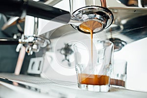 Finish of the espresso extraction process from bottomless portafilter in a glass cup photo