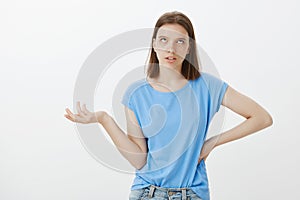 Finish your talk I am bored. Indifferent careless snobbish woman in blue t-shirt, holding hand on hip, rolling eyelids