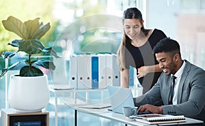 Finishing up right on time. two businesspeople working together on a laptop in an office.