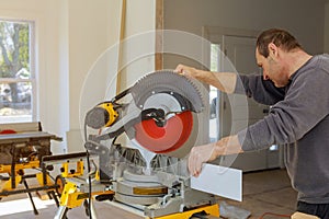 finishing work the worker cuts the wood moldings baseboard on the miter saw