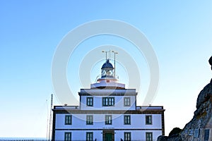 Finisterre lighthouse with sunset light and shadows. Red and blue colours, clear sky. Galicia, Fisterra, Spain.