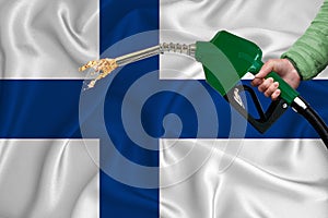 FINLAND flag Close-up shot on waving background texture with Fuel pump nozzle in hand. The concept of design solutions. 3d