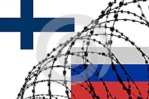Finland and Russian flags separated by a barbed wire fence. Concept symbolizing tense relations between countries