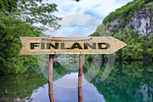 Finland wooden arrow road sign against lake in the forest background. Travel to Finland  concept