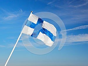 Finnish flag on the flagpole against the blue sky.