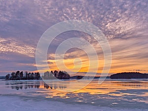 Finnish frozen lake with tree reflections at sunset